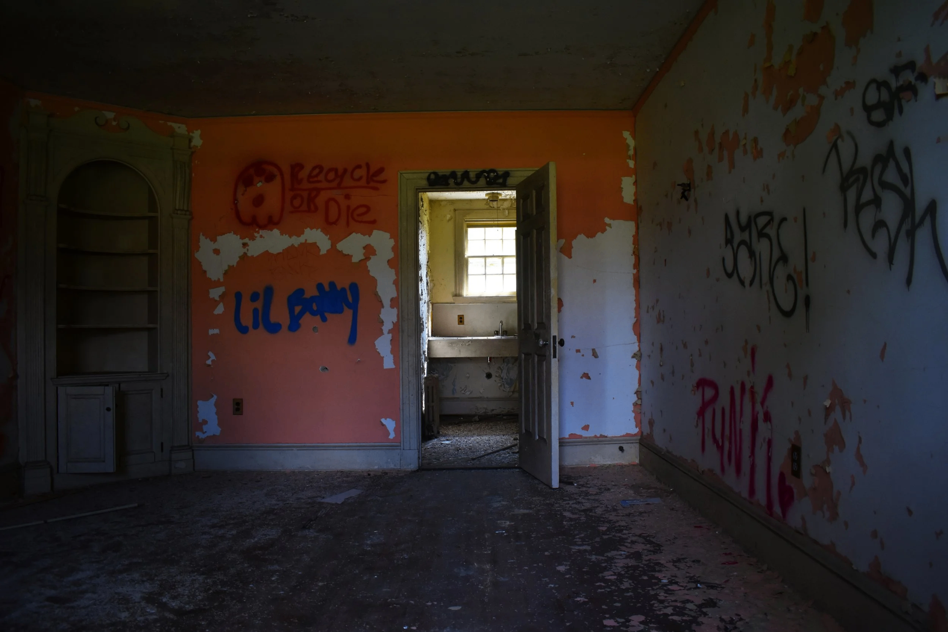 An empty patient room with paint peeling off the walls.
